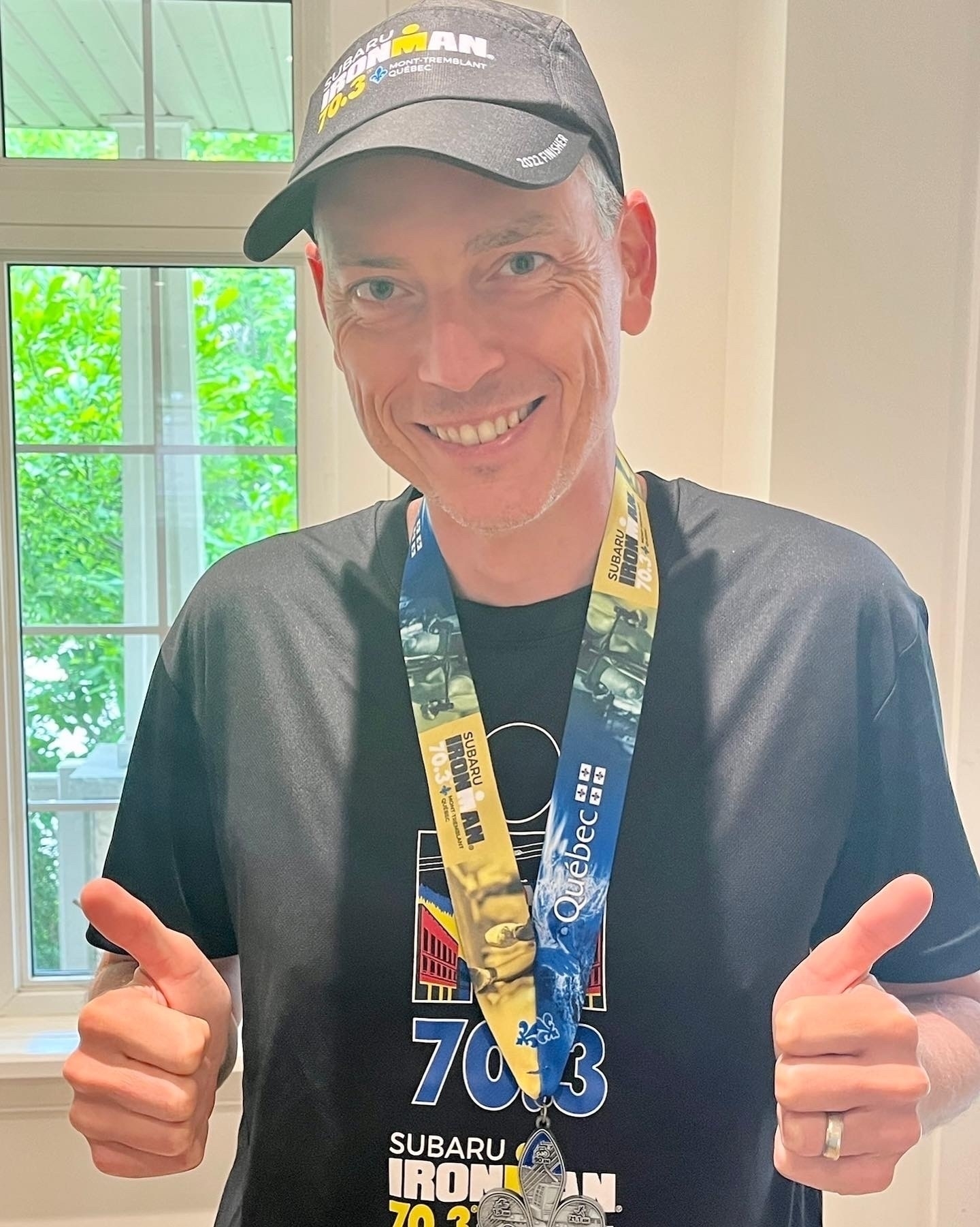 Me wearing all the event swag (hat, shirt, and medal) with two thumbs up