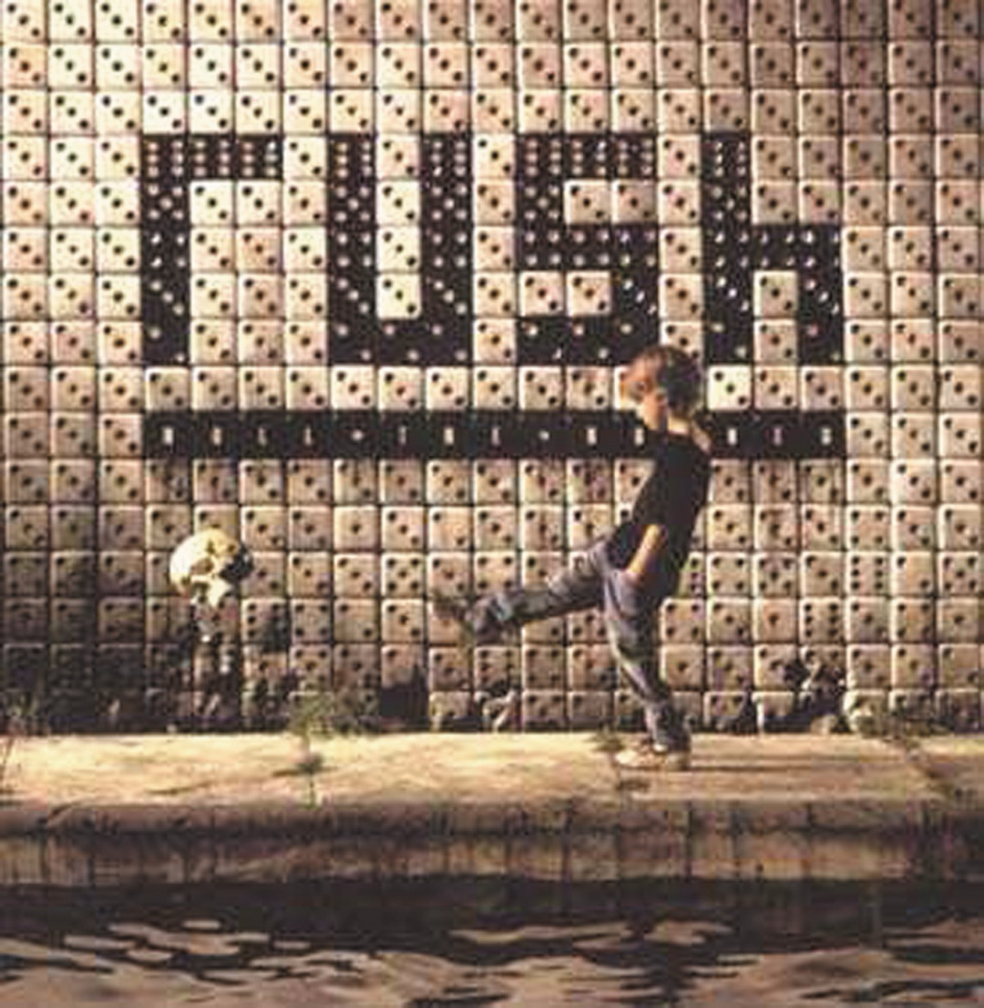 A person kicks a can in front of a wall with the word Rush displayed on it.